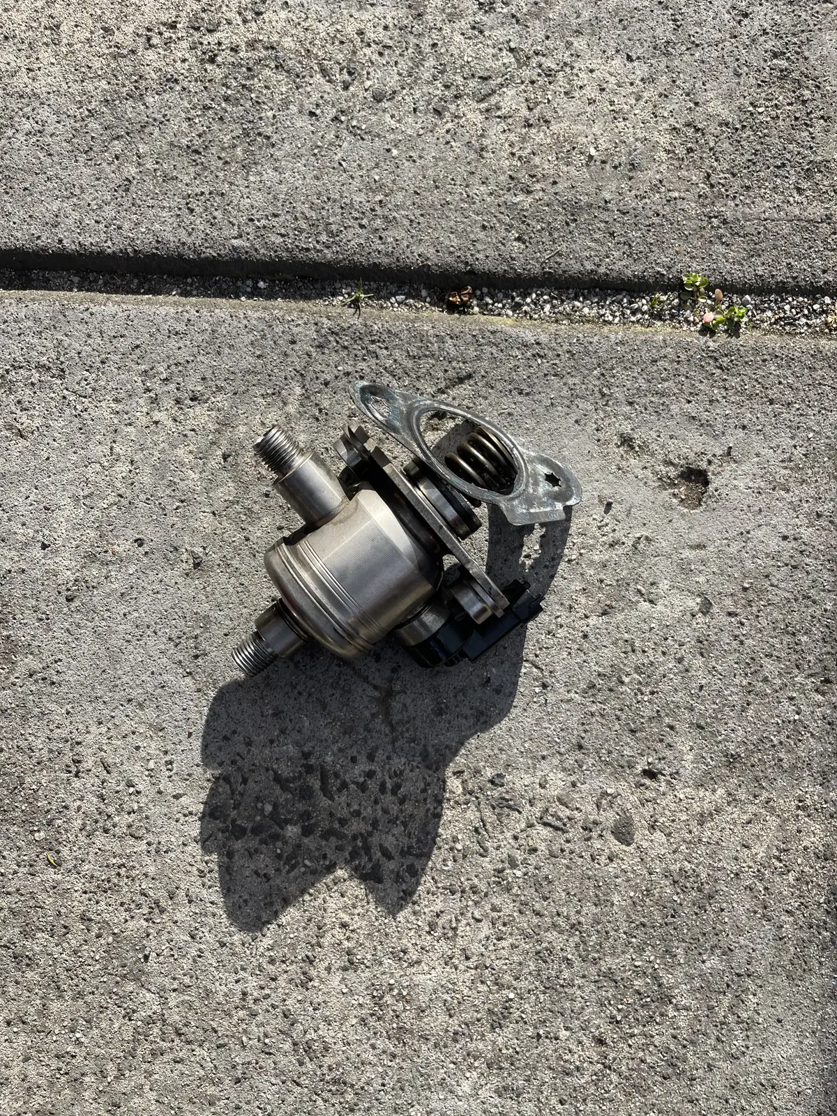Removed high-pressure fuel pump with its spring and mounting flange visible