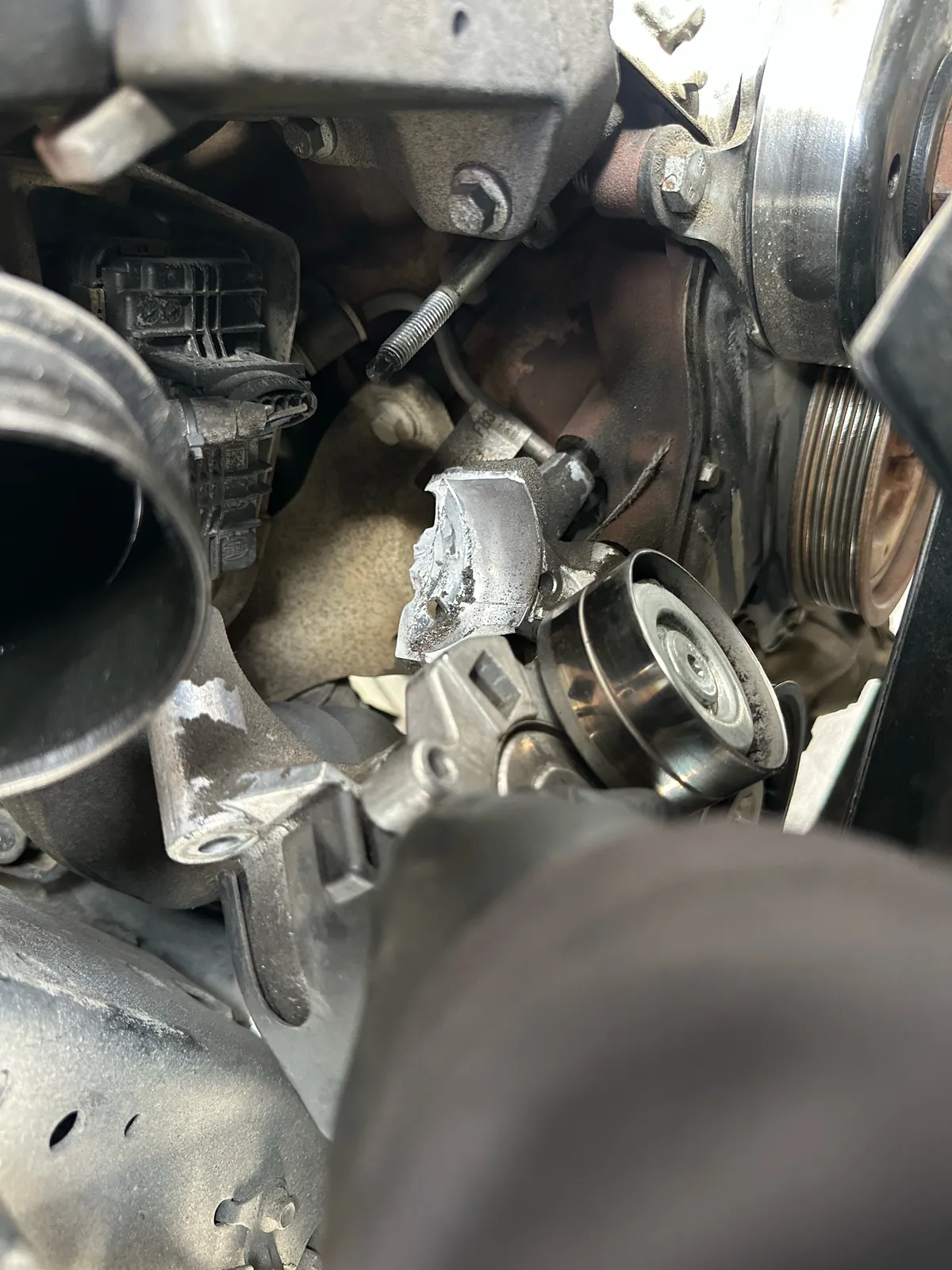 Broken Ford Ranger drive belt tensioner with a fractured housing in the engine bay